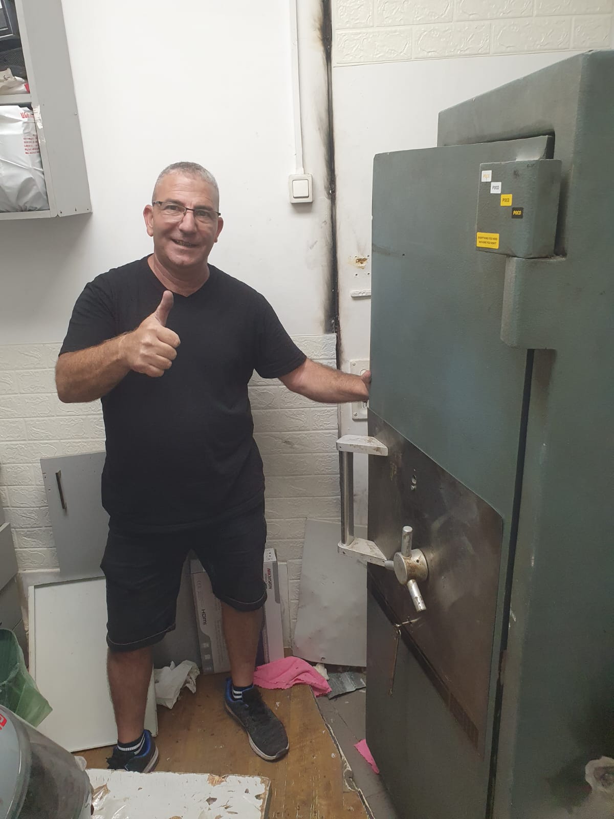 שלום, טכנאי כספות מוסמך, ליד דלת כספת כבדה פתוחה